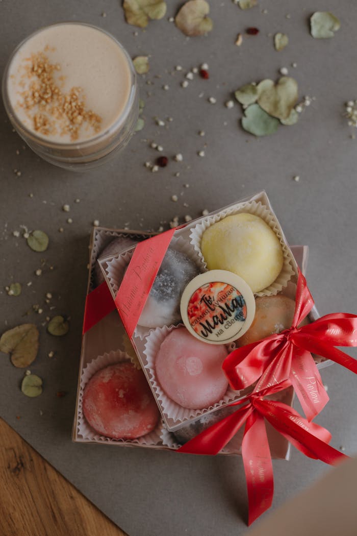 Top view of a colorful mochi dessert box and cappuccino. Perfect for food lovers.